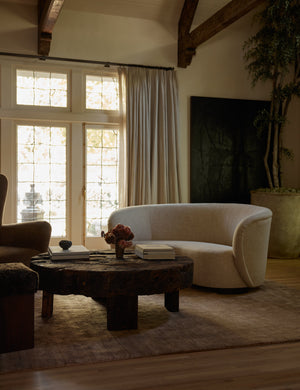 The Chiltern mauve rug lays in a dark living room under a linen sofa, a round wooden coffee table, and a brown accent chair