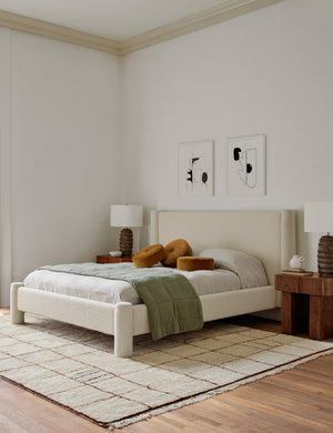 Ivory and ochre Irregular Grid Rug by Sarah Sherman Samuel lays in a bedroom with a natural linen framed bed and a ripple accent chair
