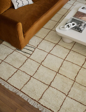 Ivory and ochre Irregular Grid Rug by Sarah Sherman Samuel lays under a conganc velvet sofa and a rounded coffee table