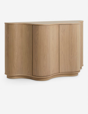 Angled view of the Cora half-moon, wavy light-wood sideboard