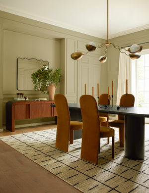 Kukka large modern wavy arm chandelier in brass hanging over a table in a dining room