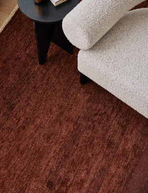 The Heritage brick rug lays under a black circular side table and a white boucle accent chair