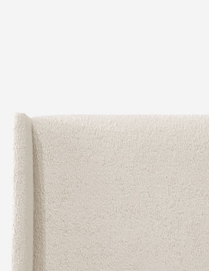 Close-up of the subtle winged headboard and trim lines on the Adara cream sherpa upholstered bed.