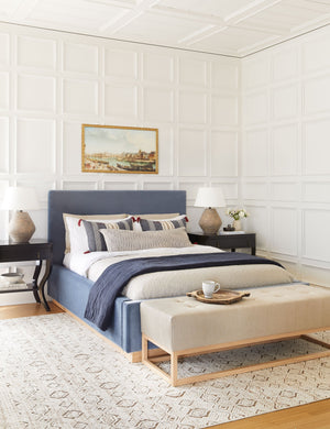 Two Khala table lamps with ribbed bases and weathered finishes sit atop black nightstands in a bedroom with a blue linen bed in between them