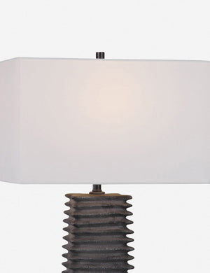 Close-up of the Neva gray table lamp with ribbed base and metallic glaze with its light on