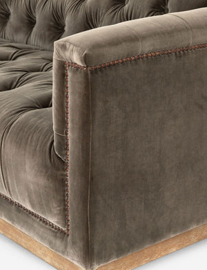 Close-up of the right arm of the Afia tufted gray-brown velvet sofa with nailhead trim and light wood base