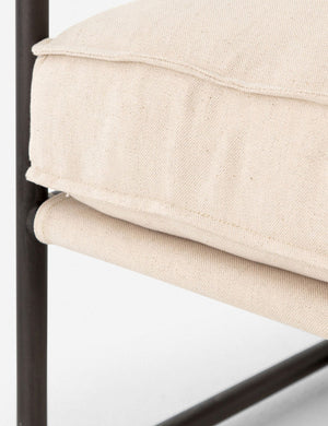 Close-up of the black metal frame and seat cushioning on the Alena accent chair with cream linen cushions