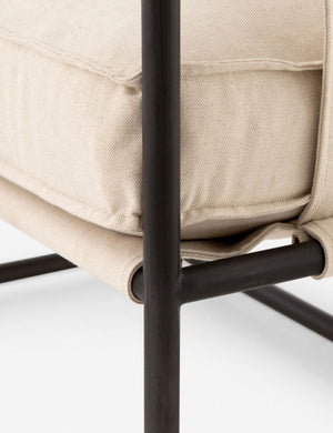 Close-up of the black metal frame and seat cushioning on the Alena accent chair with cream linen cushions