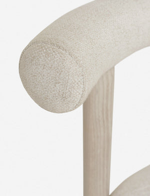 Close-up of the back edge of the Dame minimalist rounded open-back dining chair with ivory upholstered seat and ash wood frame