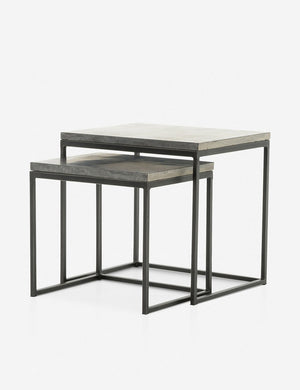 Angled view of the Ginette bluestone nesting side tables with black metal legs with the smaller table half way under the larger table