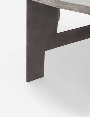 Close-up of the iron leg on the base of the Andra round coffee table with light mango wood top and iron X-base