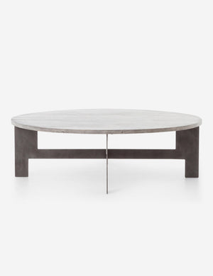 Side view of the Andra round coffee table with light mango wood top and iron X-base