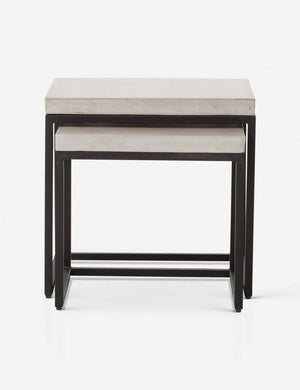 The Kallia indoor and outdoor nesting side tables with iron bases and concrete tops with the smaller table half nested into the bigger table