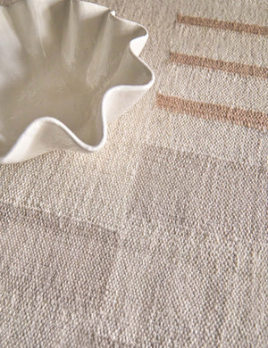 The Ruffle ceramic cream centerpiece bowl by Regina andrew sits atop a natural toned carpet