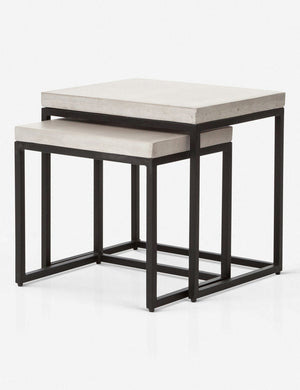 Angled view of the Kallia indoor and outdoor nesting side tables with iron bases and concrete tops with the smaller table half nested into the bigger table