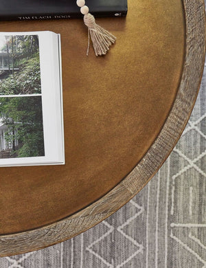 Bird’s–eye view of the rimmed surface of the Becca coffee table with iron tripod-style base with two books sitting atop it